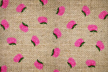 burlap background with a pink pattern of chrysanthemumsの写真素材