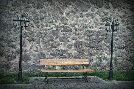 a bench and two lantern on stone wall backgroundの写真素材