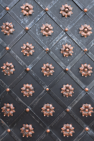 black metal door decorated with copper flowers closeupの写真素材