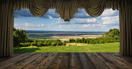 summer landscape with meadows and fields in the distance behind a window with curtainsの写真素材
