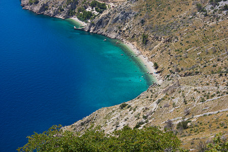 A turquoise sea with a steep rocky shoreの写真素材