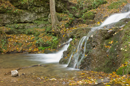 landscape with a small waterfall in an autumn forestの写真素材