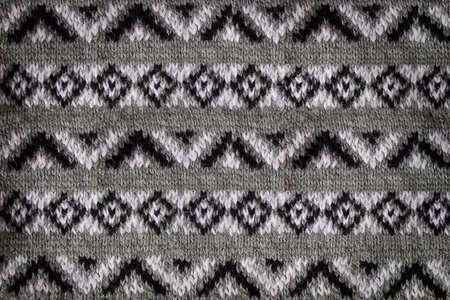 Close-up jacquard texture knitted on needles. Knitted background with black and white pattern