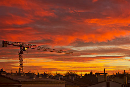 Picturesque pink sunset in the city over the rooftops. A construction crane against the background of the sunset skyの写真素材