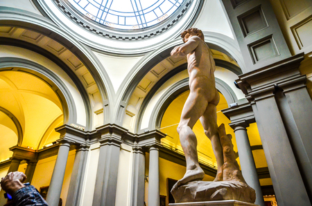 A tourist snaps away at probably the most famous sculpture in the world, The David, by Michelangelo. The marble sculpture by Michelangelo is housed at the Galleria dell'Accademia in Florenceのeditorial素材