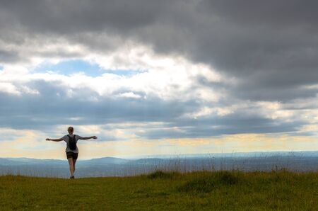 Woman with outstretched arms hiking in the countryside. View of the Cotswold Way, Englandの写真素材