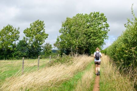 Woman hiking on a countryside footpath on the Cotswold Way, Englandの写真素材