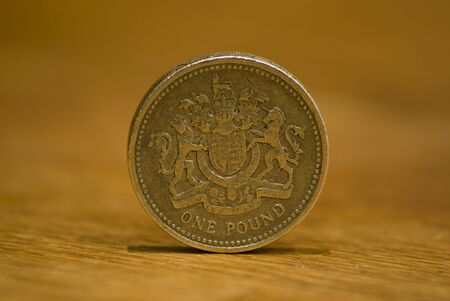 British one pound coin on a wooden table. Macro with narrow depth of field.の写真素材
