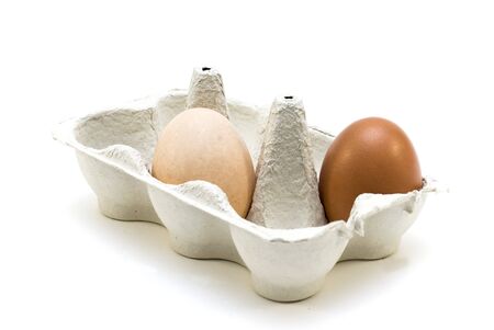 A brown and pale egg in a containerの写真素材