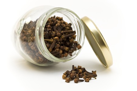 Cloves spilling out of a glass jarの写真素材