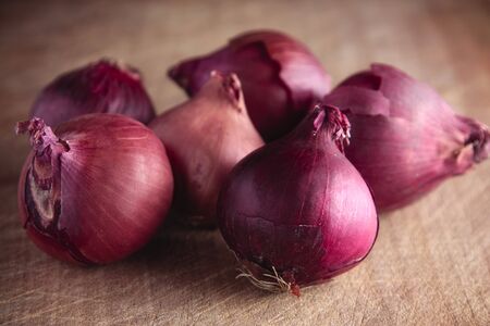 A bunch of red onions on a wooden boardの写真素材