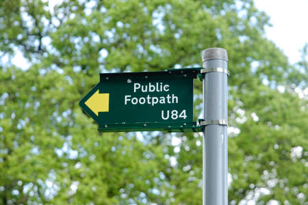 A green UK public footpath directional sign