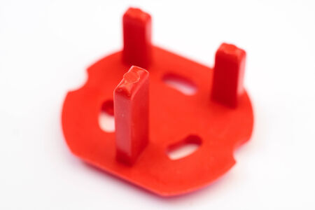 Red children's safety plug on a white background
