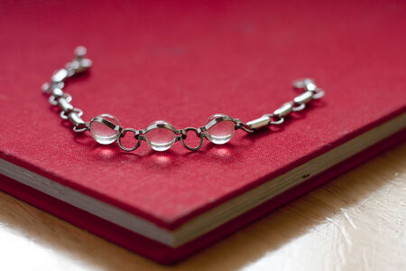 Silver bracelet with crystal balls laying on a red bookの写真素材