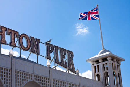 The famous sign of Brighton Pier silhouetted against a bright blue sky