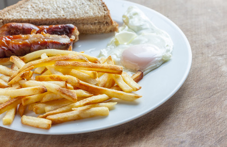 Sausage, egg and chips on a white plateの写真素材