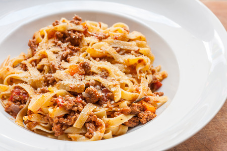 A classic traditional Italian dish, ragu all bolognese, with tagliatelle in a white bowlの写真素材