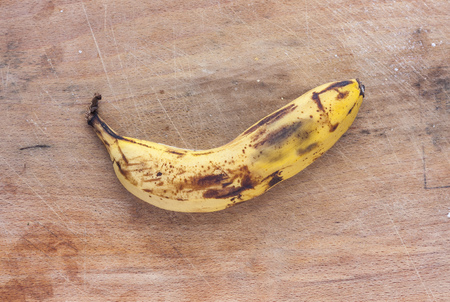 A rotten banana on a dirty mottled wooden surfaceの写真素材