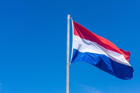National flag of the Netherlands set a aginst a stark deep blue skyの写真素材