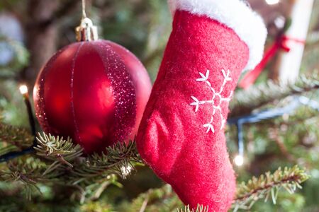 Small red stocking decoration hanging on a Christmas tree