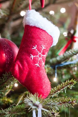 Small red stocking decoration hanging on a Christmas treeの写真素材