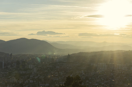 The sun's setting rays cover the hills, mountains, and buildings of Sarajevoの写真素材