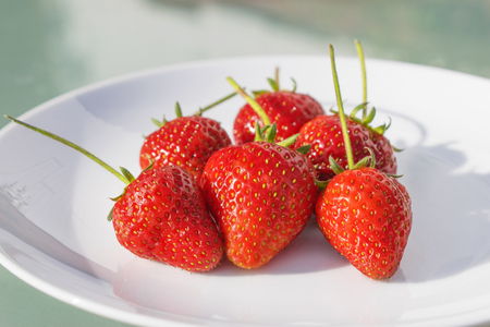 Freshly picked ripe strawberries served on a white plateの写真素材
