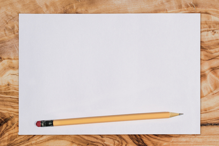 Paper and pencil on a wooden desk, viewed from above with copy spaceの写真素材