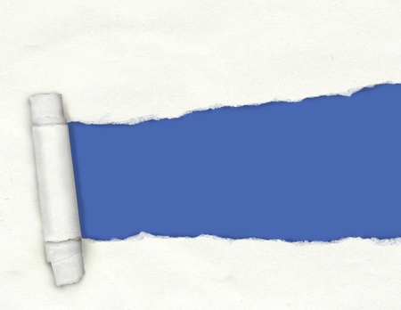 Textured white torn paper with a ripped hole showing a blue background with copy spaceの写真素材