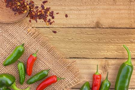 red and green chilli peppers on a rustic background viewed from the top with copy spaceの写真素材