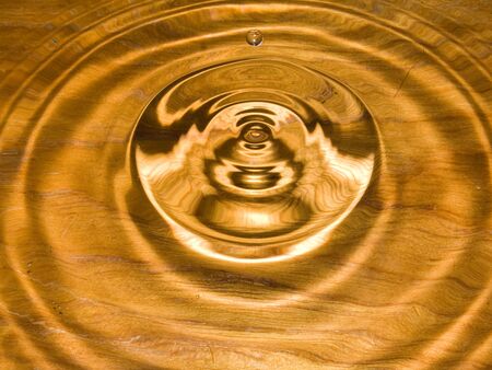 Water droplets and circular ripples on wood の写真素材