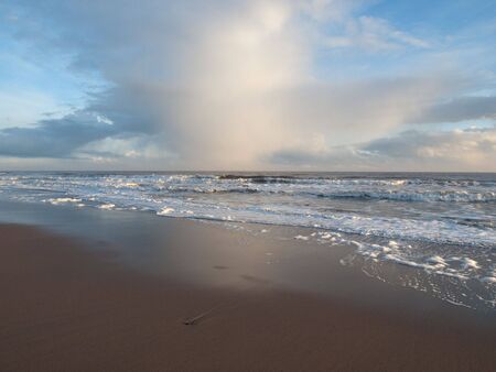 Clouds over a rough sea from the beachの写真素材