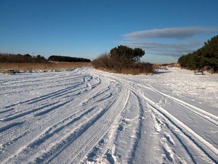 A rural landscape covered in snow with a blue sky and cloudsの写真素材