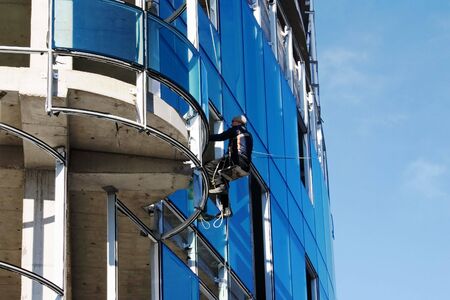 Builder fixing glass on tall buildingの写真素材