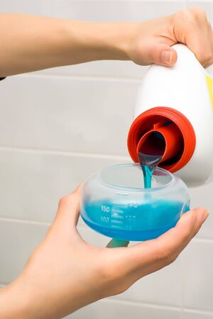 Pouring washing gel in plastic measuring containerの写真素材
