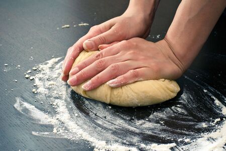 Hands kneading dough on brown wooden table