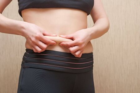 A woman shows surpluses of fat on a stomachの写真素材