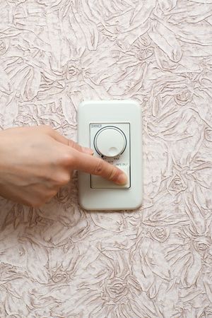 Women's hand switches off light in the room