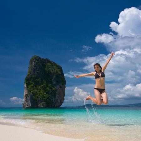 Young cheerful woman is jumping on the beachの写真素材