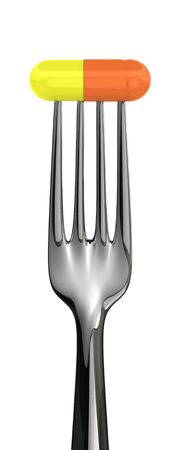 Silver fork with a pill isolated on the white backgroundの写真素材