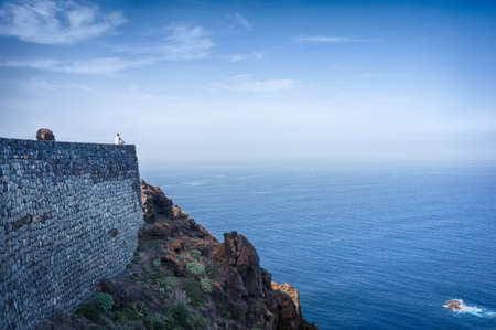 Man sitting on a wall and meditating on the oceanの写真素材