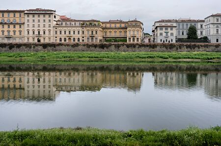 Reflection of historical buildings on the embankment in the water of Arno river in Florence, Italyの写真素材