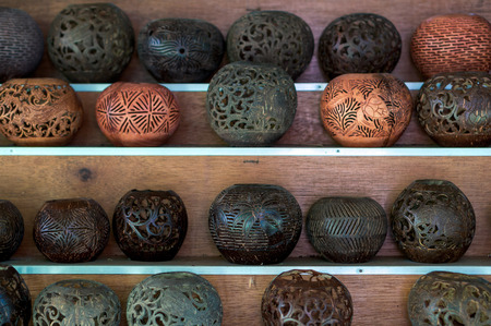Shelves with balinese souvenirs - ornamental shells for candle wich are carved from the coconut. Traditional product of handicraft on Bali, Indonesiaの写真素材