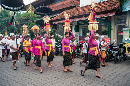UBUD, INDONESIA - OCTOBER 23, 2016: Balinese people in traditional clothes are striding along the...