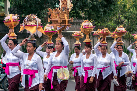 UBUD, INDONESIA - OCTOBER 15, 2016: Balinese people in traditional clothes are striding along the...