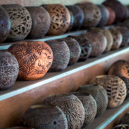 Shelves with balinese souvenirs - ornamental shells for candle wich are carved from the coconut. Traditional product of handicraft on Bali, Indonesiaの写真素材