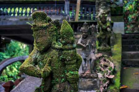 Moss-grown sculpture carved from the stone in the temple on Bali, Indonesiaの写真素材