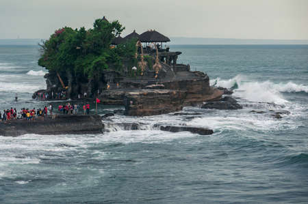 Bali, Indonesia - october 10, 2016: Tourists standing at the foot of the Tanah Lot temple in the ocean water, Bali, Indonesiaのeditorial素材