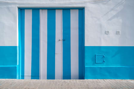 Closed gates of garage painted in blue and white colors. Urban background.の写真素材