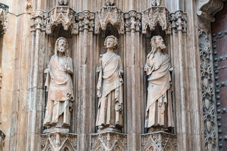 Valencia, Spain - October 28, 2019: Three statues in the niches over the entrance door of Valencia Cathedral. It is located on Plaza de la Virgen in old town.のeditorial素材